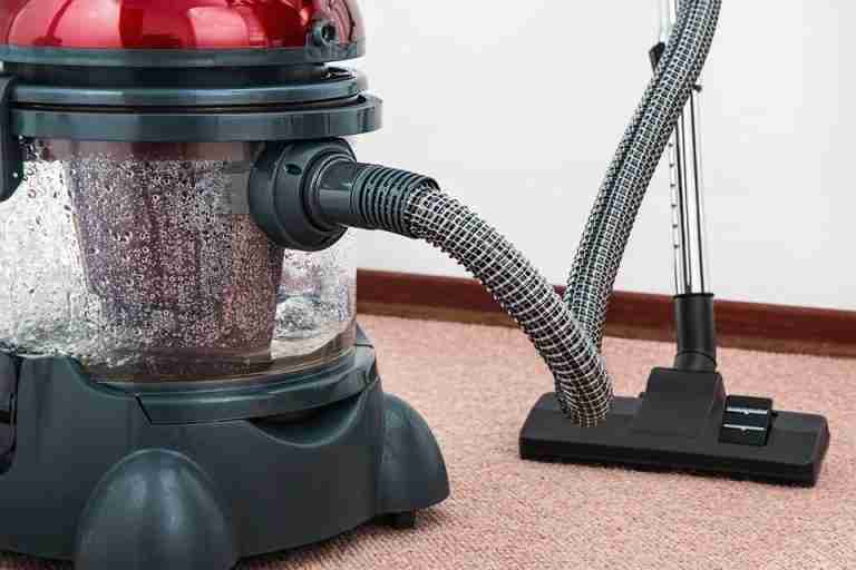 Close-up of a modern vacuum cleaner with water filtration on carpet floor indoors.